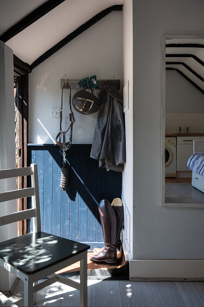 Riding boots, hat and jacket in a sunlit cottage entrance