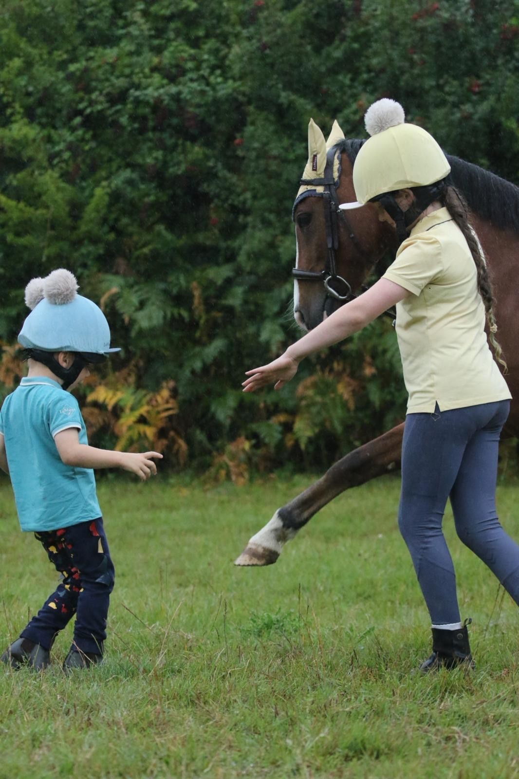 Young rider laughing alongside a pony at Hurstwood Farm